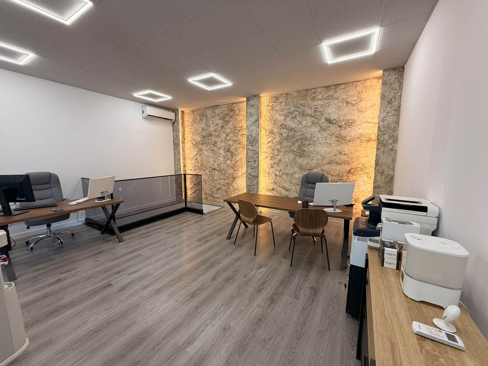 Pared de piedra iluminada en la oficina de Imperia Realty, en Calle del Jazmín, Madrid
