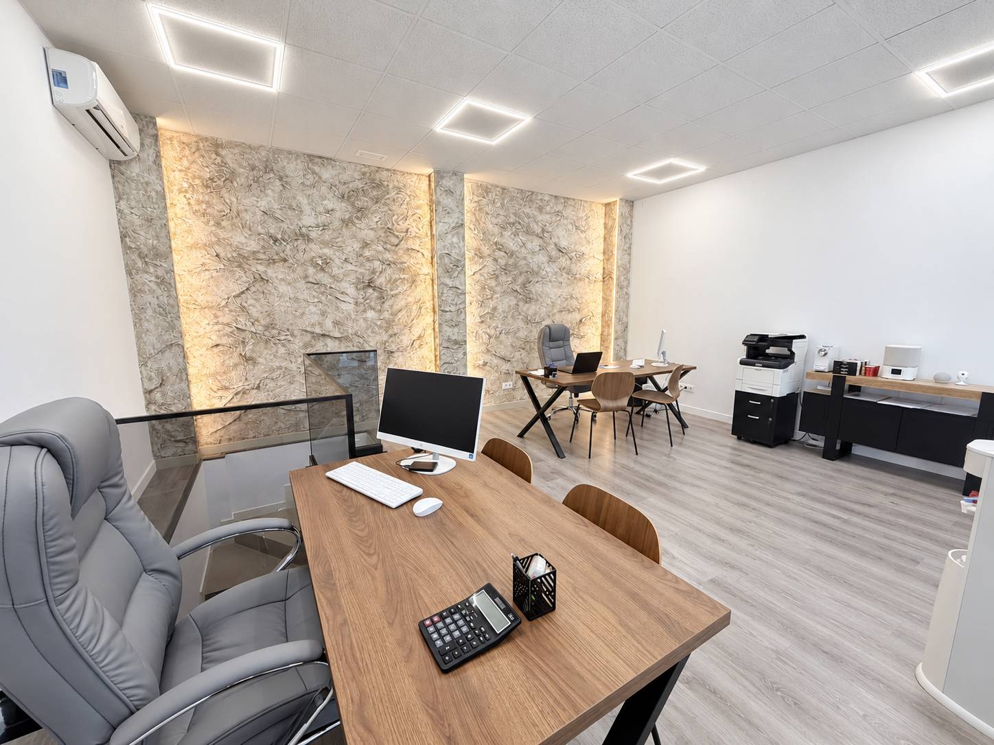 Oficina de Imperia Realty en Madrid: mesa de trabajo y pared de piedra iluminada